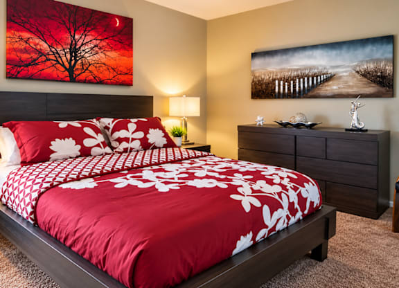 A bedroom with a red and white bedspread and two lamps on either side of the bed.