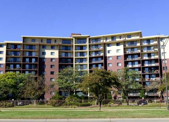 A large apartment building with a green lawn in front.