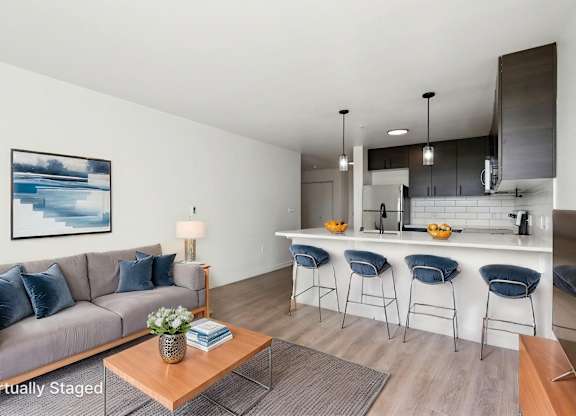 A living room with a grey couch and a coffee table with a vase of flowers on it.