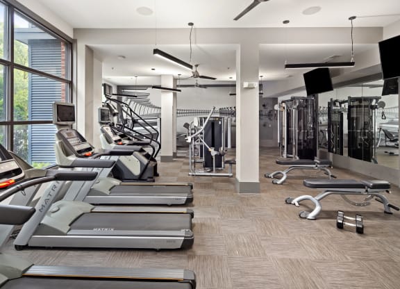 a gym with treadmills and other cardio equipment and a large window