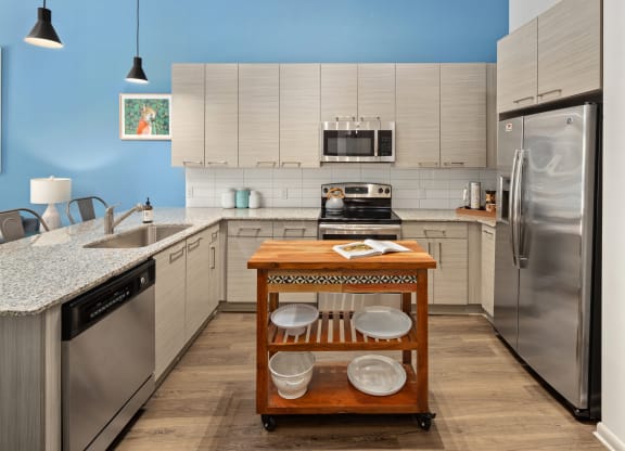 a kitchen with white cabinets and stainless steel appliances and a table with pots and pans
