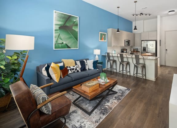 a living room with a couch and a table in front of a kitchen
