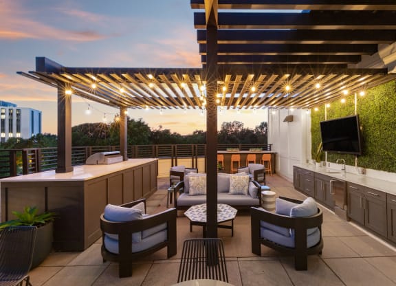 a rooftop patio with a bar and chairs and a tv