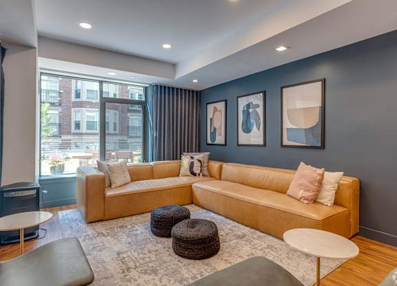 A living room with a tan couch and a grey rug.