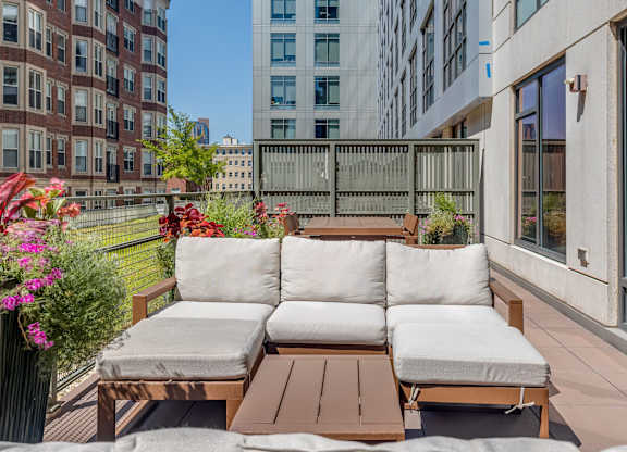 A wooden outdoor sofa with cushions is on a patio.