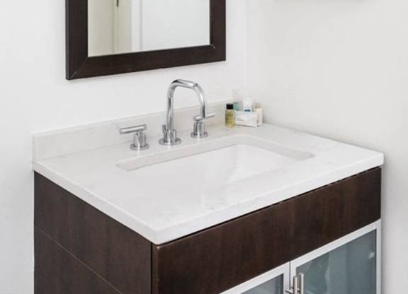 A bathroom sink with a brown cabinet and a mirror above it.