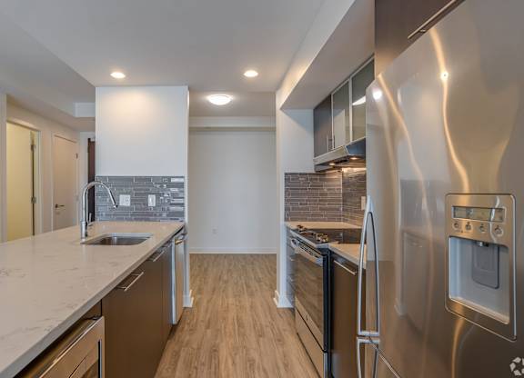 A modern kitchen with stainless steel appliances and wooden flooring.