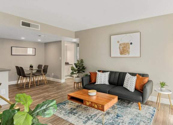 A living room with a grey couch, a wooden coffee table, and a painting on the wall.