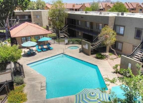 A swimming pool surrounded by a patio area with a table and chairs.