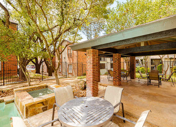 A patio with a table and chairs and a hot tub.