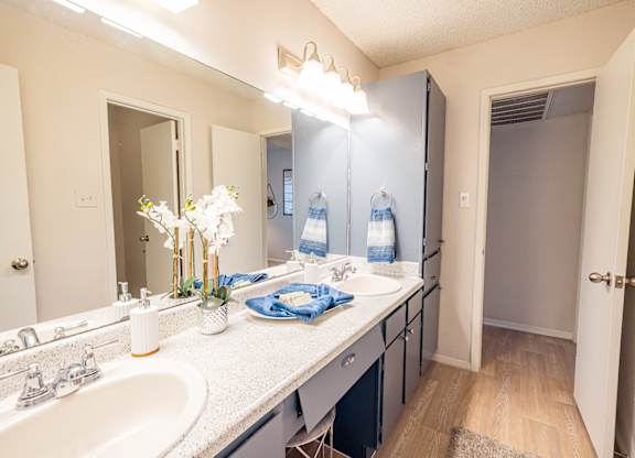 A bathroom with a sink, mirror, and a vase of flowers.