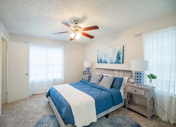 A bedroom with a bed, nightstand, and a ceiling fan.
