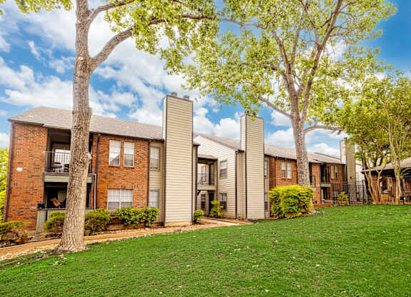 A row of apartment buildings with green lawns in front.