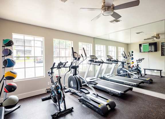 A gym with a mirror, treadmills, and exercise bikes.