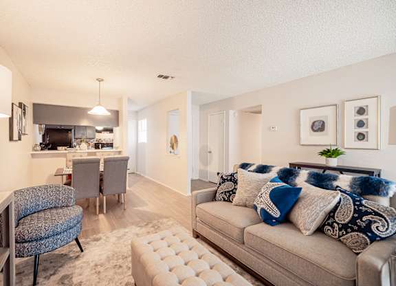 A living room with a grey couch and a white ottoman.