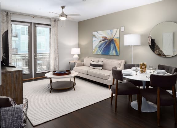 a living room and dining room with a white rug and a couch and a table