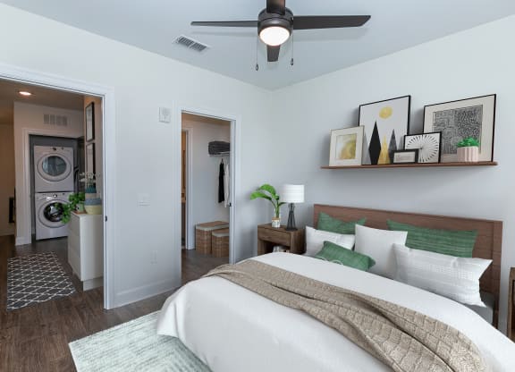 a bedroom with a bed and a ceiling fan and a washer and dryer