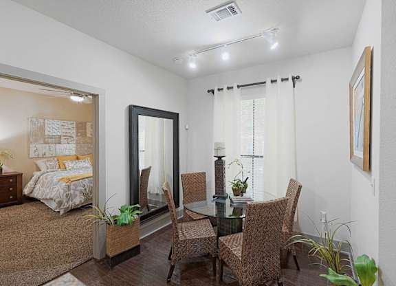 A room with a bed, a table and chairs, and a mirror.
