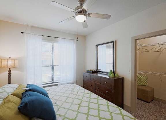A bedroom with a bed, dresser, and window.
