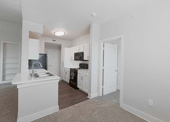 A kitchen with white cabinets and a black fridge.