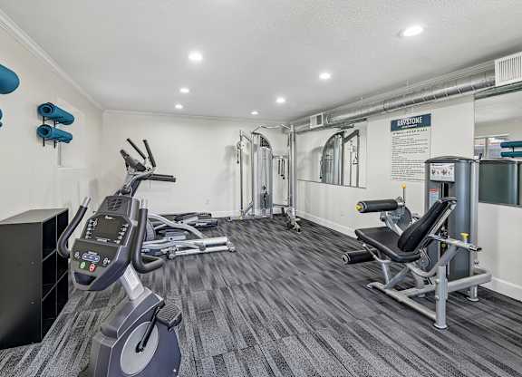 A gym with a row of treadmills and a row of exercise bikes.