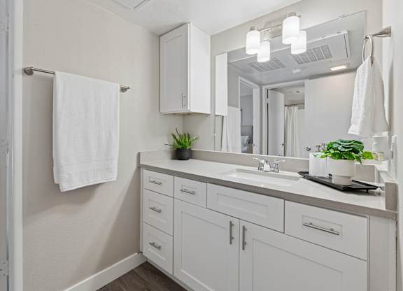A white bathroom with a mirror, sink, and towel rack.