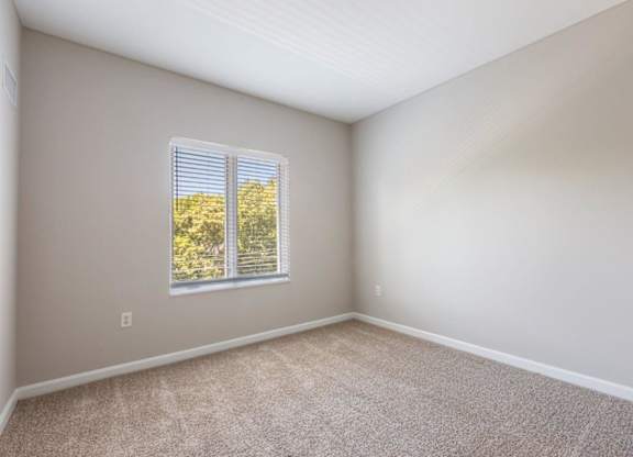 A room with a window showing trees outside.