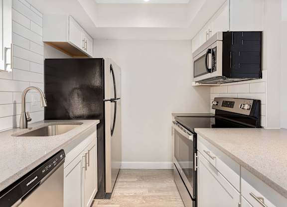 A black refrigerator stands next to a sink in a kitchen.
