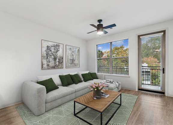 A living room with a grey couch, a coffee table, and a ceiling fan.