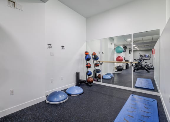 a fitness room with weights and yoga mats and a glass wall