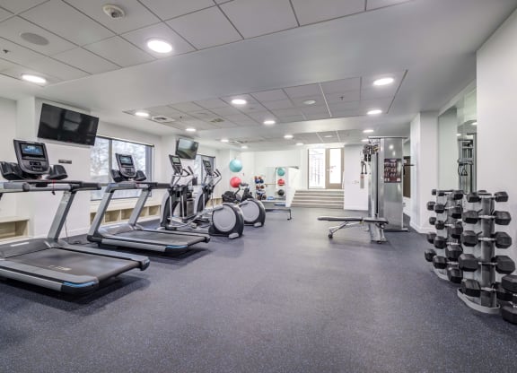 a gym with treadmills and other exercise equipment in a building with windows