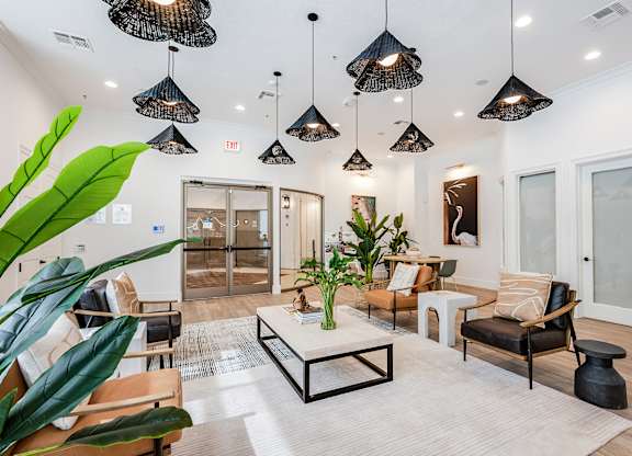 A living room with a white rug and a coffee table in the middle.