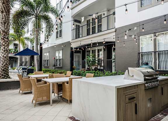 A patio with a table, chairs, and a grill.