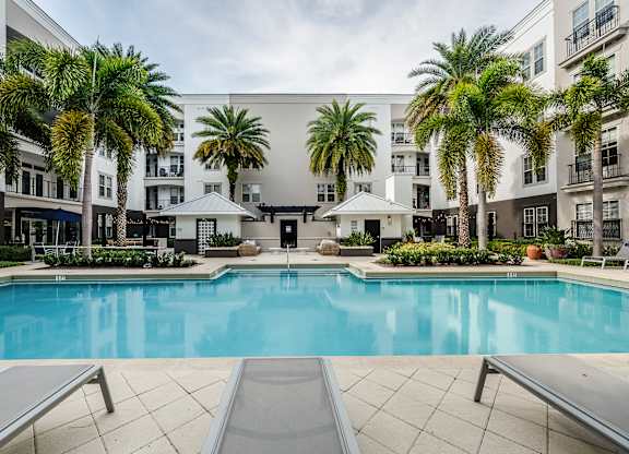 A large swimming pool surrounded by palm trees and lounge chairs.