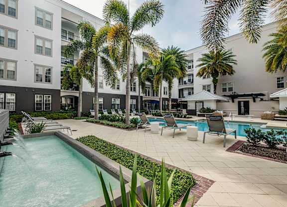 A pool surrounded by palm trees and chairs.