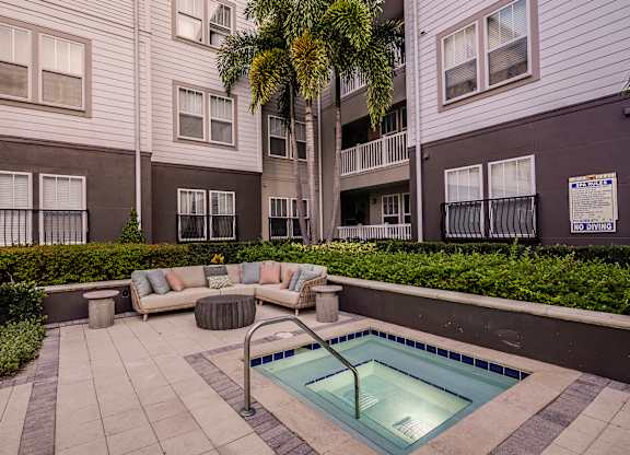 A pool surrounded by a patio and a building.