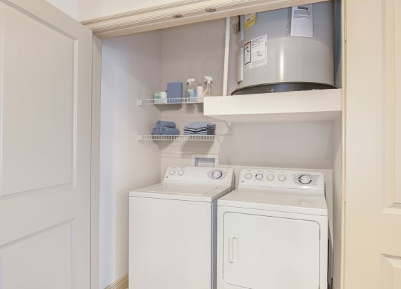 a small laundry room with a white washer and dryer and a shelf above