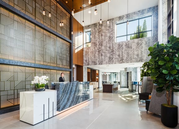 a lobby with a reception desk and a large plant at 100 House Apartments, New Jersey