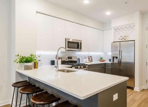 a kitchen with stainless steel appliances and an island with stools at One Ten Apartments, Jersey City , NJ, 07310
