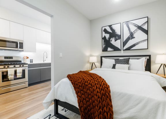 a bedroom with a large bed and a kitchen at One Ten Apartments, Jersey City