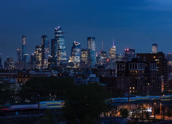 a view of the city skyline at night at One Ten Apartments, New Jersey, 07310