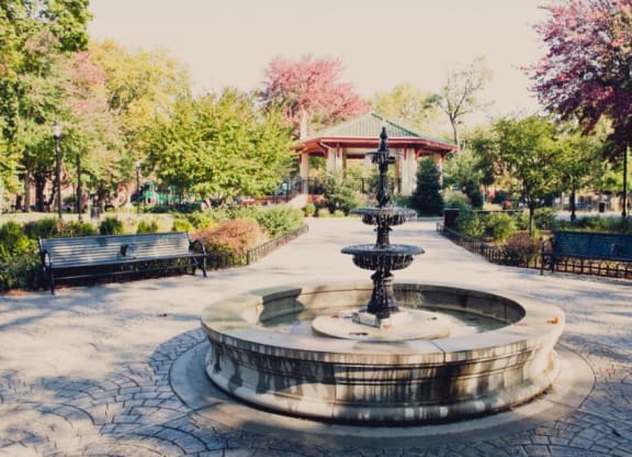 a fountain in a park with benches and a gazebo at One Ten Apartments, New Jersey, 07310
