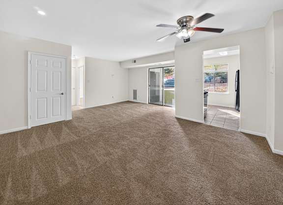 A spacious room with a carpeted floor and a ceiling fan.
