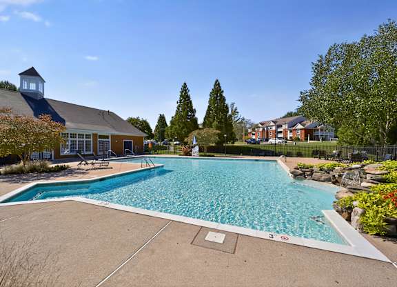 A large outdoor swimming pool surrounded by trees and a building.