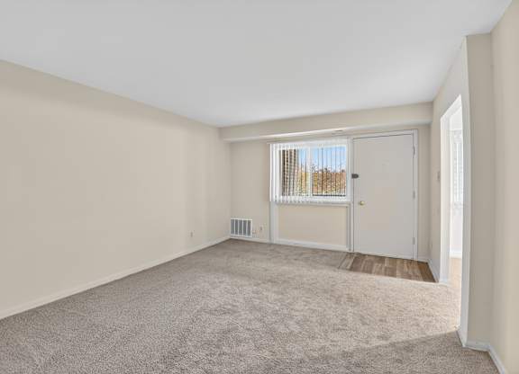A room with a carpeted floor and a sliding glass door.