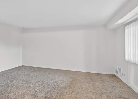 A large, empty room with carpeted floor and white walls.