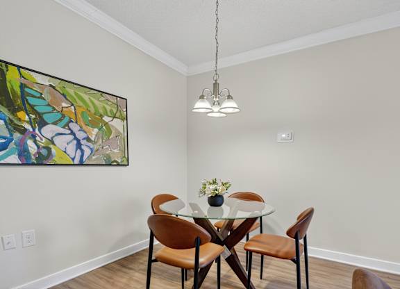 A dining room with a table set for two and a painting on the wall.