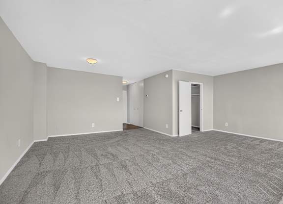 A spacious room with grey carpeting and white walls.