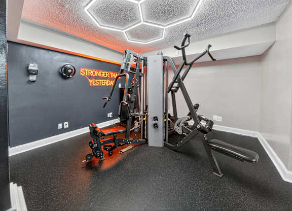 A gym room with a rowing machine and a weight machine.