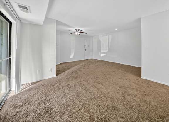 A room with a carpeted floor and a ceiling fan.